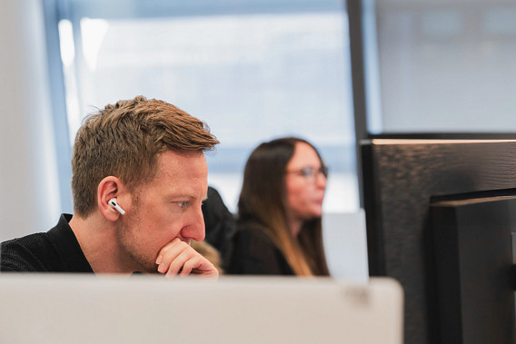 Close up of a member of staff sat at his desk, focus on their